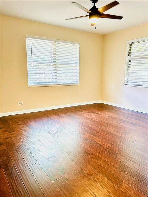 empty room with a ceiling fan, baseboards, and wood finished floors