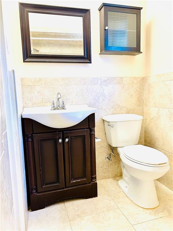 bathroom with tile patterned floors, vanity, tile walls, and toilet