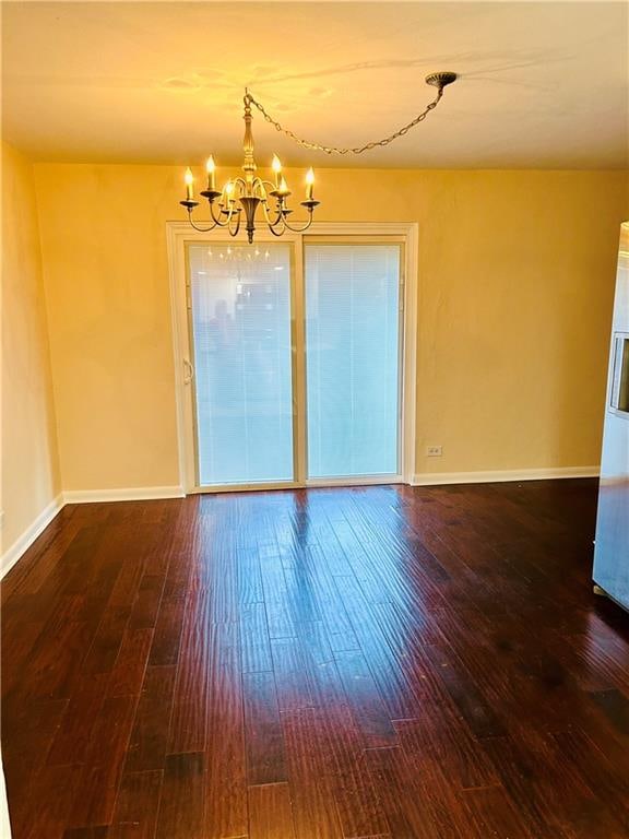 empty room with hardwood / wood-style floors and an inviting chandelier