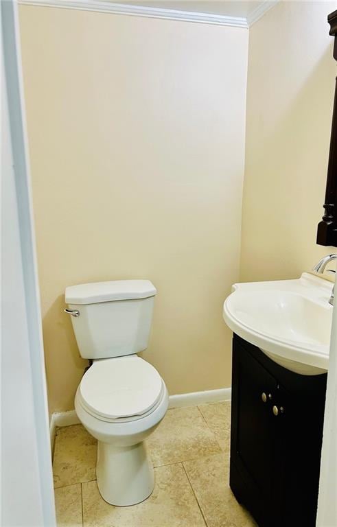 bathroom with tile patterned floors, ornamental molding, vanity, and toilet