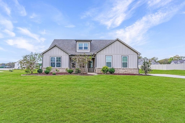 view of front of house with board and batten siding, fence, roof with shingles, and a front lawn