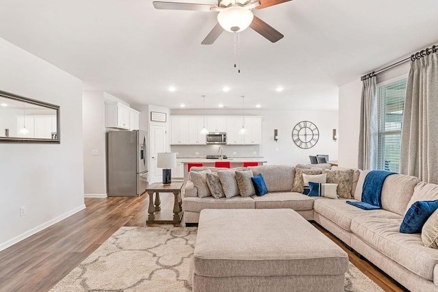 living area featuring baseboards, a ceiling fan, wood finished floors, and recessed lighting