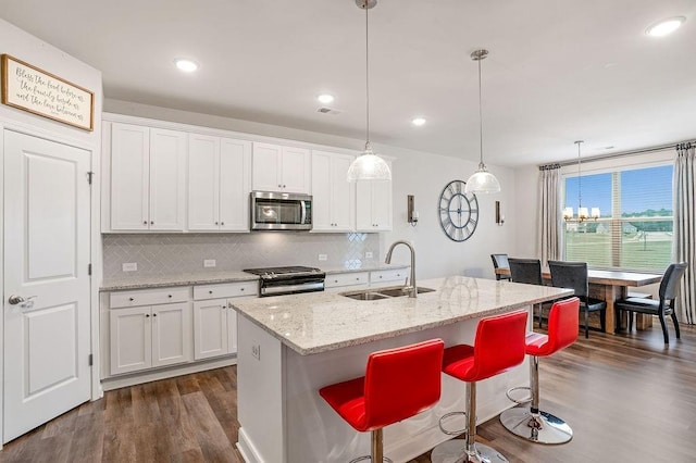 kitchen featuring a sink, backsplash, stainless steel appliances, and dark wood-type flooring