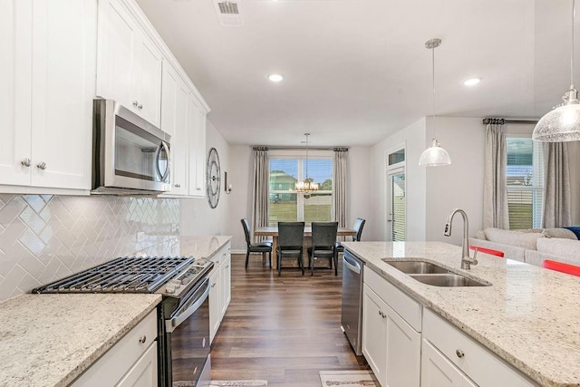 kitchen featuring backsplash, appliances with stainless steel finishes, a sink, dark wood-style floors, and white cabinetry