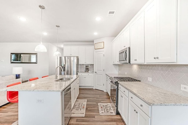 kitchen featuring visible vents, appliances with stainless steel finishes, wood finished floors, a sink, and white cabinets