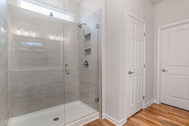 full bath featuring baseboards, a shower stall, and wood finished floors