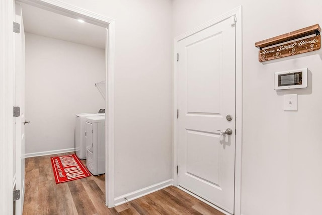 laundry area featuring laundry area, baseboards, washing machine and dryer, and wood finished floors