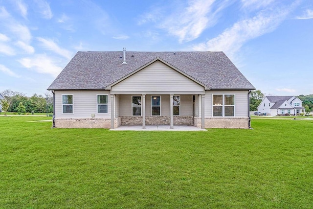 rear view of property featuring a shingled roof, a yard, and a patio area