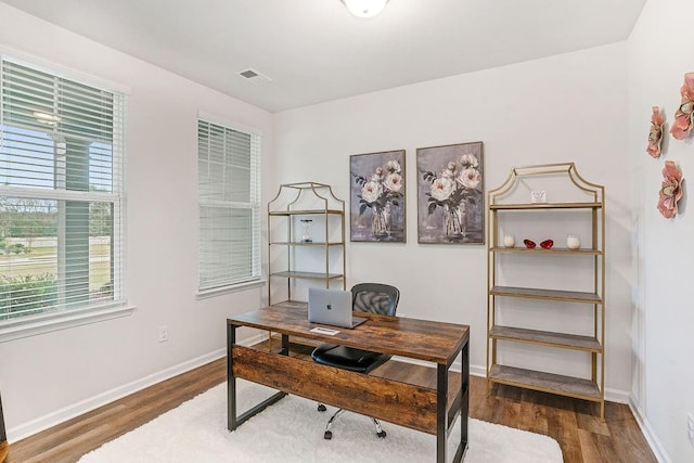 office area featuring baseboards, plenty of natural light, wood finished floors, and visible vents