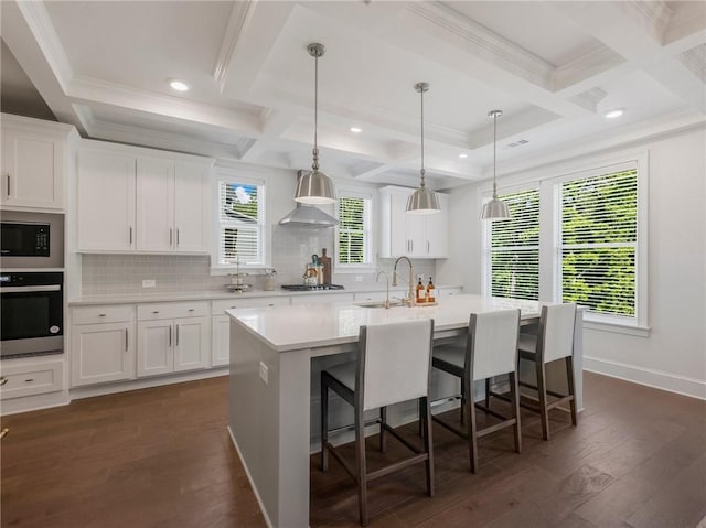 kitchen with a center island with sink, white cabinetry, stainless steel appliances, and dark hardwood / wood-style flooring