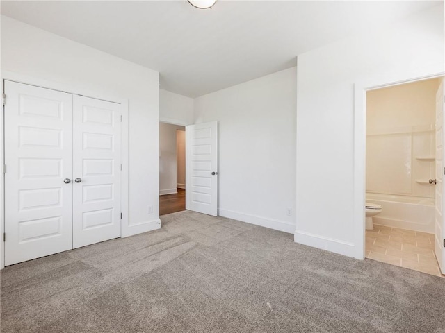 unfurnished bedroom featuring connected bathroom, carpet floors, and a closet