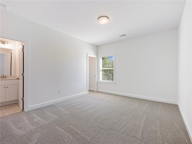 spare room with sink and light colored carpet