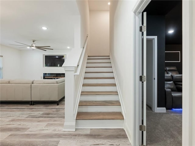 stairs with hardwood / wood-style flooring and ceiling fan