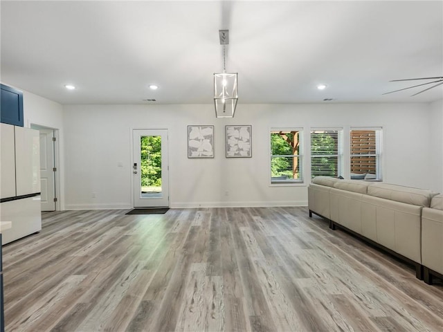 unfurnished living room featuring light hardwood / wood-style floors and a notable chandelier