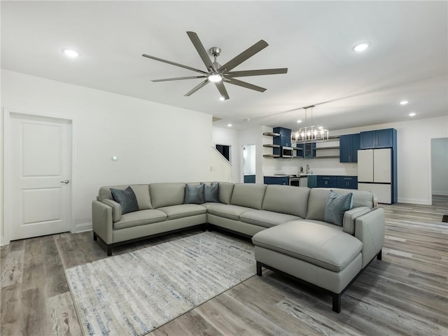 living room featuring ceiling fan with notable chandelier and hardwood / wood-style floors