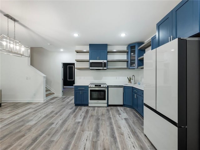 kitchen featuring appliances with stainless steel finishes, blue cabinets, sink, and light wood-type flooring