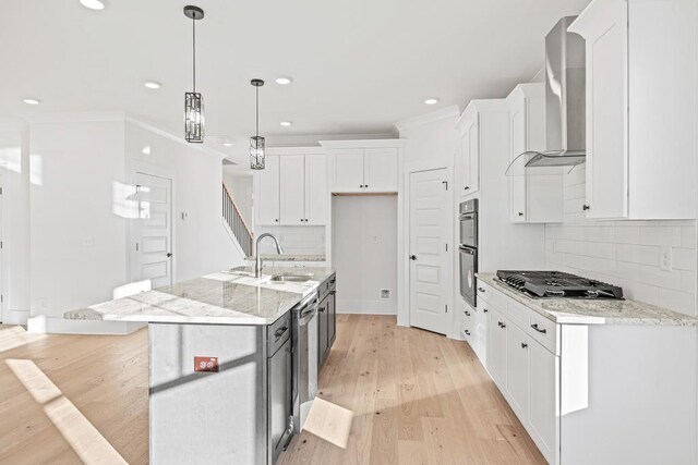 kitchen featuring white cabinetry, stainless steel gas cooktop, a kitchen island with sink, light stone countertops, and sink