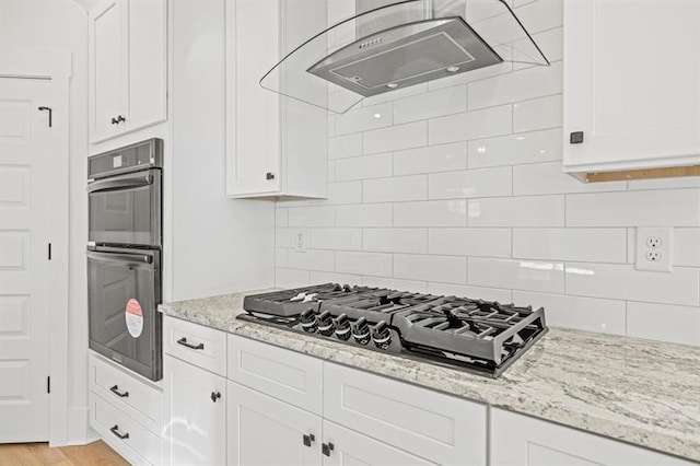kitchen with light stone counters, white cabinetry, black appliances, and range hood