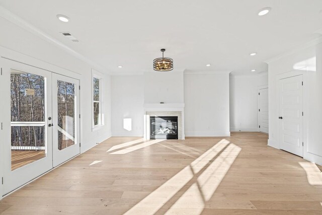 unfurnished living room with light hardwood / wood-style flooring, crown molding, and french doors