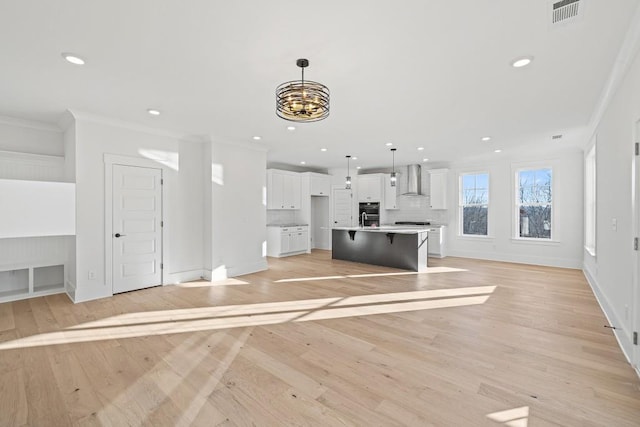 unfurnished living room featuring light hardwood / wood-style floors, crown molding, and an inviting chandelier