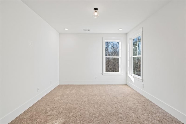spare room featuring baseboards, recessed lighting, visible vents, and light carpet