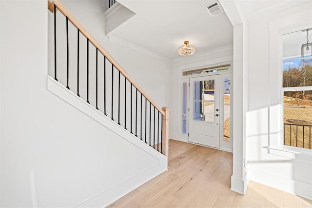 entrance foyer featuring stairway, ornamental molding, wood finished floors, and visible vents