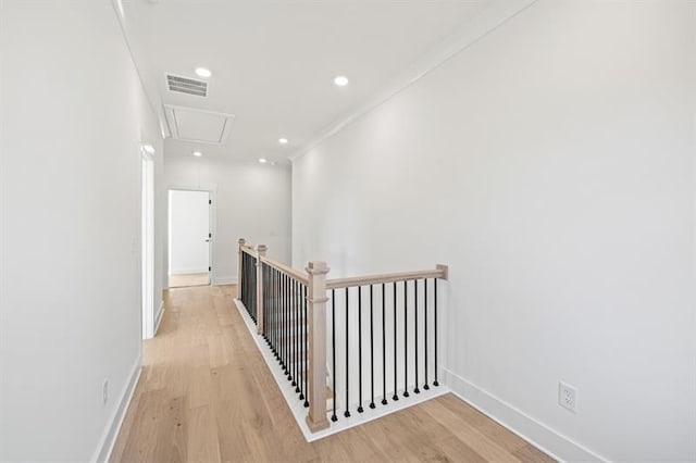 hallway featuring light wood-style floors, baseboards, attic access, and visible vents
