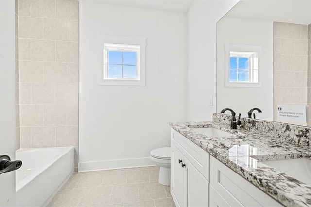 full bath featuring a sink, toilet, double vanity, a bathtub, and baseboards