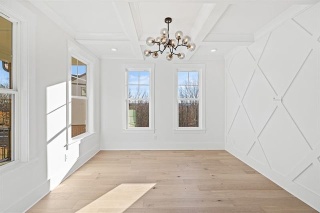 unfurnished dining area with an inviting chandelier, beam ceiling, baseboards, light wood-style floors, and coffered ceiling