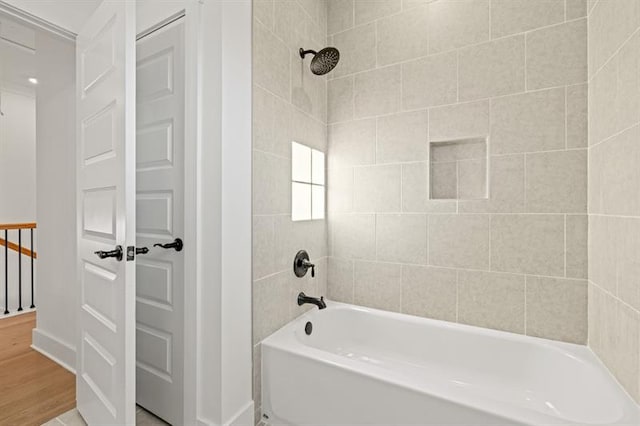 bathroom with baseboards,  shower combination, and wood finished floors