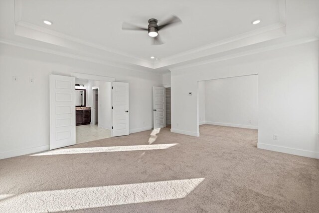 unfurnished bedroom featuring ornamental molding, light carpet, connected bathroom, and a raised ceiling