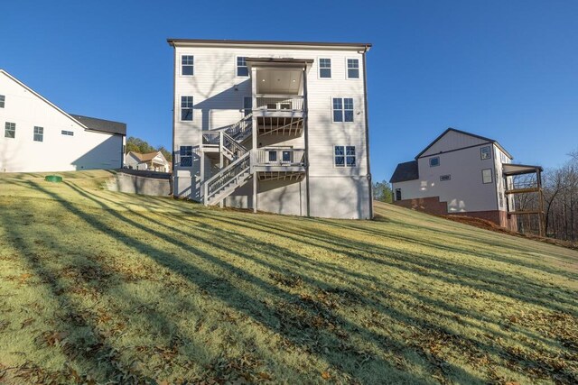 back of property with a yard, a balcony, and central air condition unit