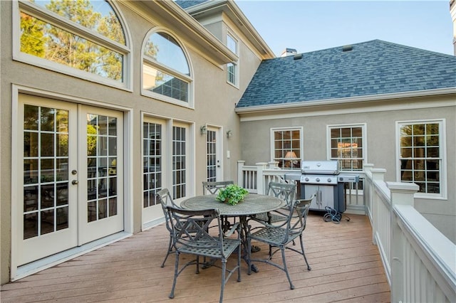 wooden deck with outdoor dining space, french doors, and grilling area