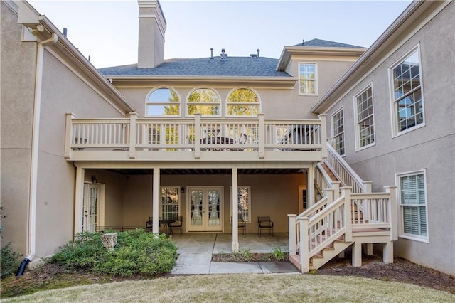 back of property with french doors, stairway, stucco siding, a chimney, and a patio area