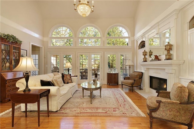 sunroom with a chandelier, a lit fireplace, french doors, and plenty of natural light