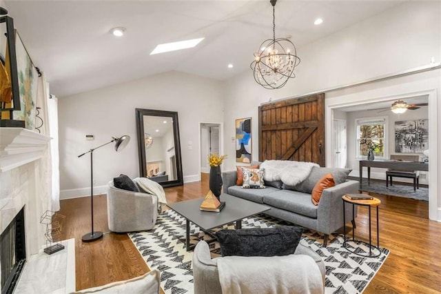 living area featuring a premium fireplace, a chandelier, baseboards, wood finished floors, and lofted ceiling