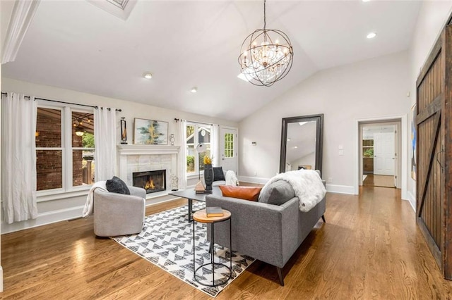 living room with wood finished floors, a warm lit fireplace, healthy amount of natural light, vaulted ceiling, and recessed lighting