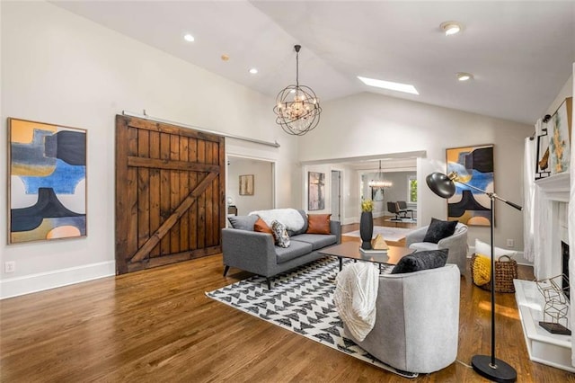 living area featuring a chandelier, a barn door, wood finished floors, vaulted ceiling, and baseboards