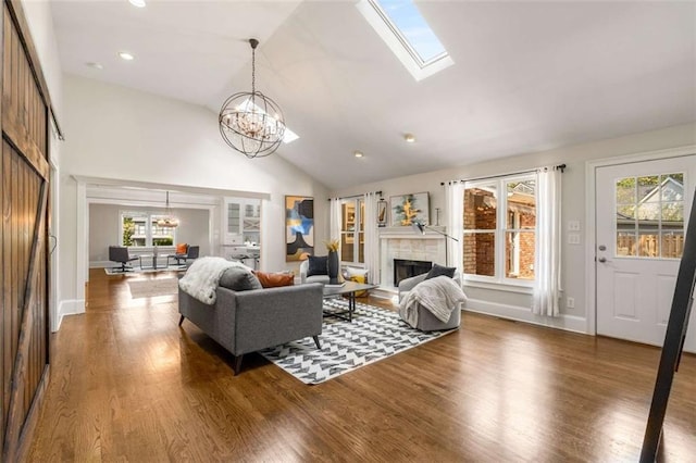 living area with a chandelier, a fireplace, wood finished floors, baseboards, and high vaulted ceiling