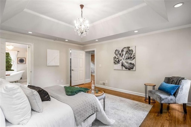 bedroom with a tray ceiling, a chandelier, wood finished floors, baseboards, and ornamental molding