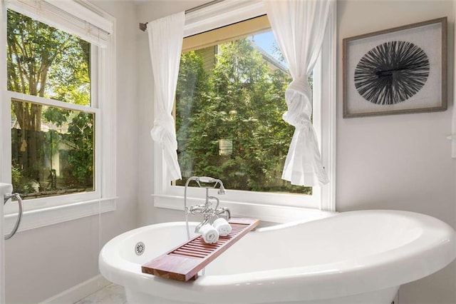 full bath featuring a freestanding bath and baseboards