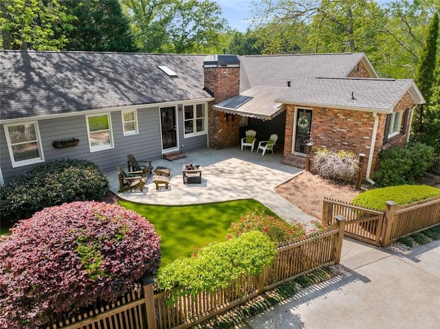 rear view of house featuring an outdoor fire pit, a patio, a chimney, and roof with shingles