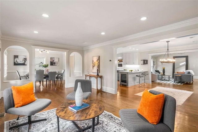 living area featuring beverage cooler, arched walkways, a chandelier, light wood-type flooring, and recessed lighting