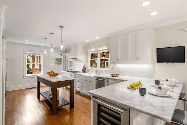 kitchen with beverage cooler, a sink, custom range hood, stainless steel appliances, and crown molding