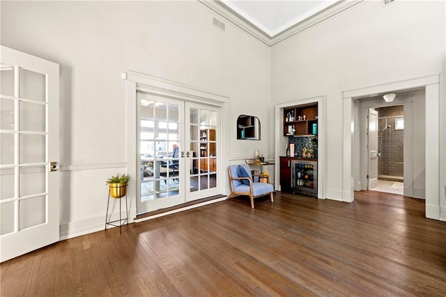 unfurnished room with wood finished floors, french doors, wine cooler, a high ceiling, and crown molding