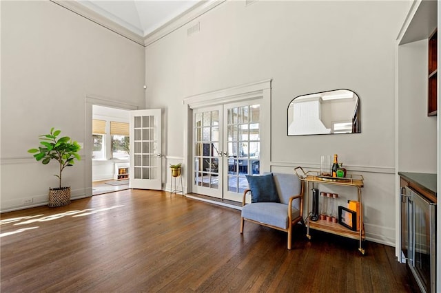 sitting room with visible vents, wood finished floors, french doors, baseboards, and a towering ceiling