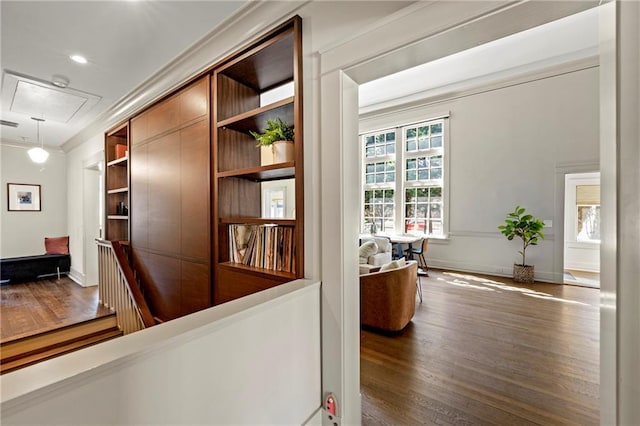 hallway with baseboards, dark wood-type flooring, attic access, and ornamental molding