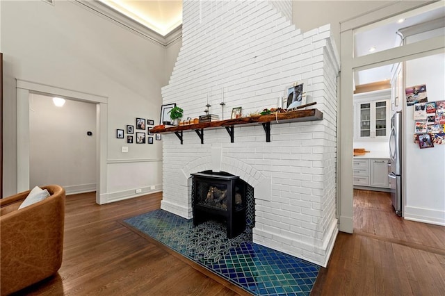 living area with brick wall, a high ceiling, baseboards, and wood finished floors