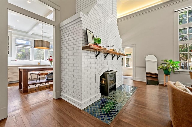 living area with dark wood-style floors, beamed ceiling, and a healthy amount of sunlight