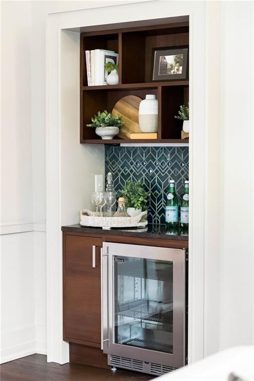 bar featuring dark wood finished floors, wine cooler, tasteful backsplash, and a dry bar